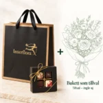 Presentkit Lyx: svart presentpåse från Interflora och chokladask med praliner, plus en tecknad bukett som tillval – buketten ingår inte.